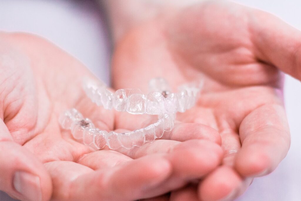 Clear aligner trays held in open hands